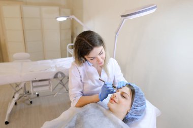 Profesyonel güzellik uzmanı tarafından kaş dövme kalemi kadın için makyaj yapma.