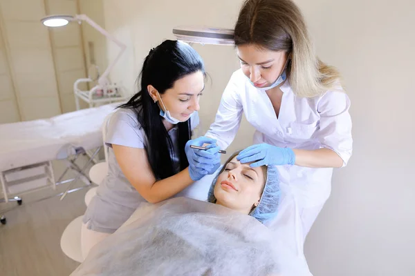 Caucasian woman visiting professional dermatologist and cosmetologist for permanent makeup.