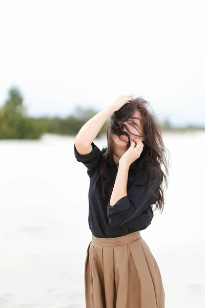 Chica vistiendo camisa negra y falda de pie en blanco nieve fondo monótono . —  Fotos de Stock