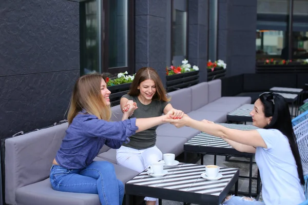 Felices amigas sentadas en la cafetería y cogidas de la mano . — Foto de Stock