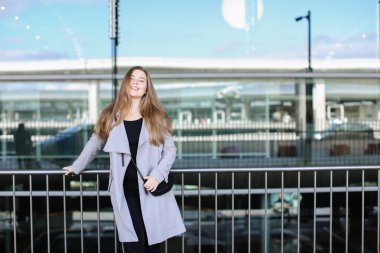 Tren İstasyonu yakınında duran ve çanta ile gri ceket giyen kadın kişi.