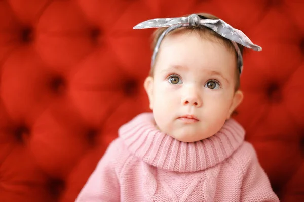 Closeup female child wearing pink sweater sitting in red background. — Stock Photo, Image
