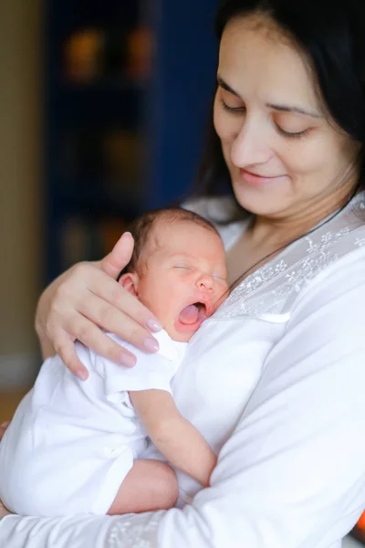 Молодая счастливая мать в белой одежде держит новорожденного ребенка . — стоковое фото