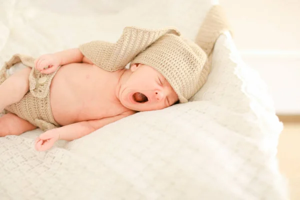 Cute newborn baby yawning, sleeping and wearing crocheted clothes. — Stock Photo, Image