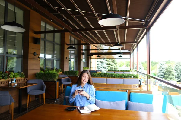 Mujer bebiendo café en la cafetería y sentado con teléfono inteligente y portátil . — Foto de Stock