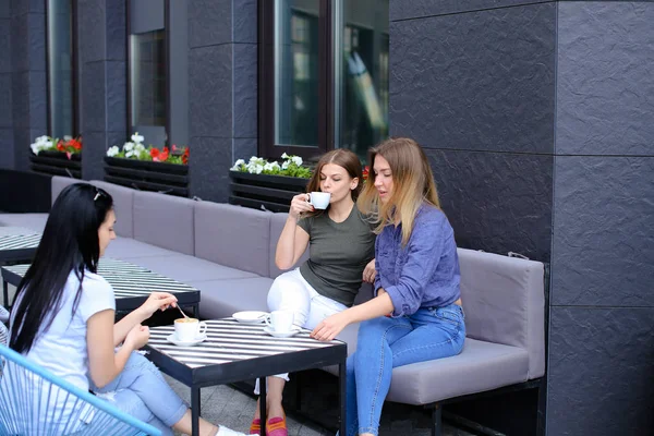 Felices amigas tomando café y sentadas en la cafetería . — Foto de Stock