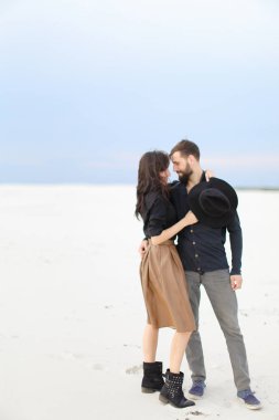 Etek ve siyah gömlek giyen kış kar tek sesli arka planda, sarılma genç mutlu çift.
