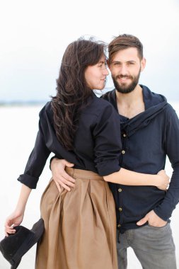 Birbirlerine sarılma ve tek sesli kış arka planda moda giysiler giyen genç gülümseyen çift.