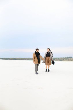 Beyaz çocuk ve kat ve tulum giyen yürüyüş ve beyaz kış arka planda elele kız.