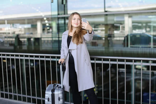 Hübsche Frau macht Selfie mit Smartphone in der Nähe von Flughafen und Flughafen. — Stockfoto
