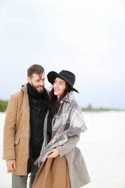 Gelukkige vrouw en man dragen van jassen en sjaals die permanent in de winter sneeuw achtergrond. — Stockfoto