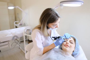 Gülümseyen kadın alma kaşları Bakanlar Kurulu profesyonel güzellik uzmanı, dövme.