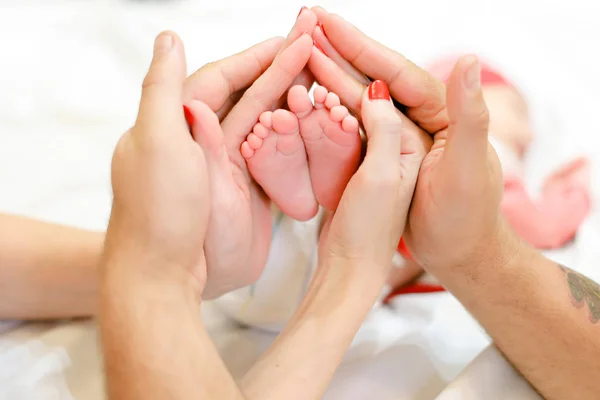 Yeni doğan bebek bacakları holding ebeveyn eller. — Stok fotoğraf