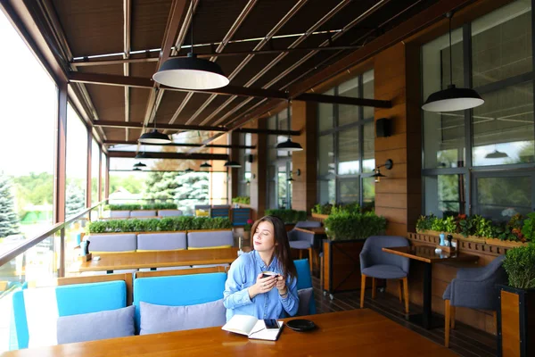 Estudiante caucásico sentado en la cafetería con portátil y teléfono inteligente, beber café . — Foto de Stock