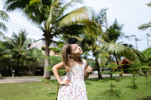 Маленькая кавказская девочка, стоящая рядом с пальмами и дорогой на заднем плане . — стоковое фото