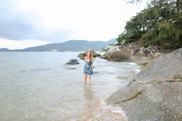 Yalınayak kumsalda, sabah deniz kıyısında yürüyen genç güzel kadın.