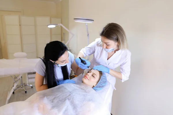 Jolie femme se faisant maquiller professionnel permanent par un cosmétologue et une infirmière . — Photo