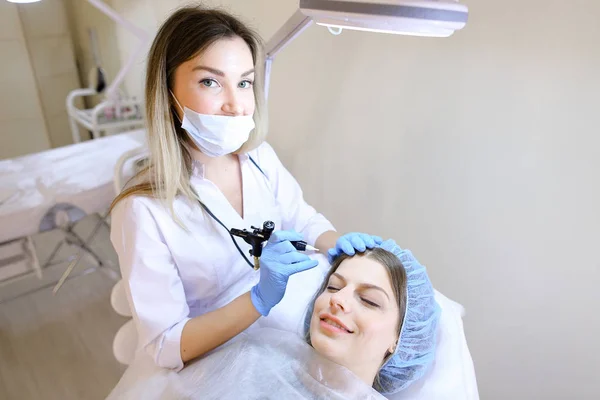 Mujer encantadora consiguiendo procedimiento permanente cualificado del maquillaje por el cosmetólogo . — Foto de Stock