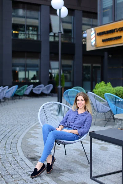 Alegre persona femenina sentada en silla con fondo de edificio . — Foto de Stock