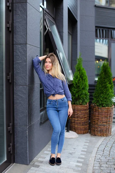 Стильная девушка, стоящая возле здания и зеленого растения . — стоковое фото