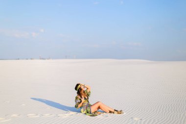 Wh üzerinde oturan Siyah mayo ile yeşil plaj elbise giyen kadın