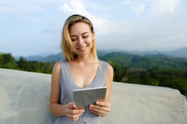 Genç güzel kadının Dağları arka planda yeni tablet.