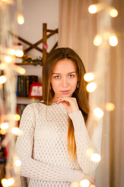 Jong meisje permanent in de buurt van geel twinkling slingers op kamer. — Stockfoto