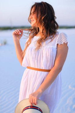 Elbise ve ha tutmak beyaz kum üzerinde duran genç kadın