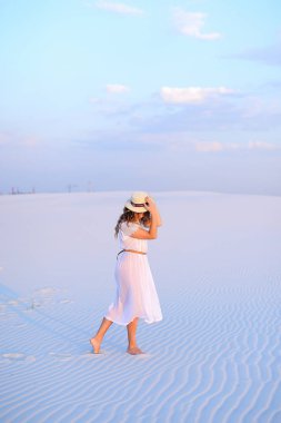 Beyaz elbise ve san üzerinde yürüyüş şapka giyen genç beyaz kadın