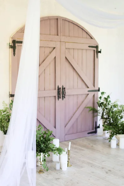 Dos velas cerca de puerta de madera y plantas . — Foto de Stock