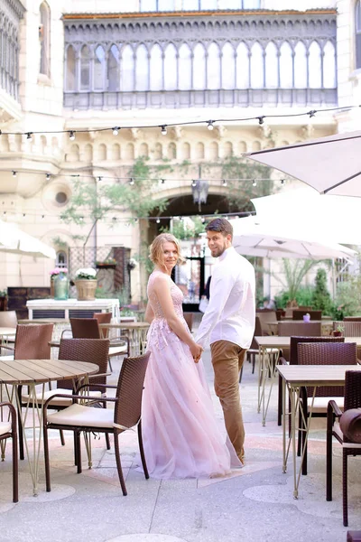Feliz noivo caucasiano e noiva em pé no restaurante perto da mesa e do edifício no fundo . — Fotografia de Stock