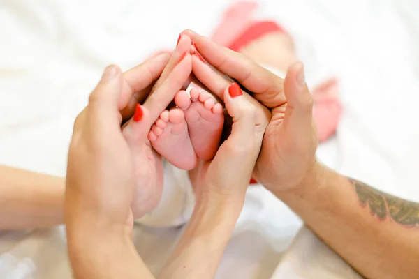 Matka i ojciec trzymając się za ręce noworodków baby nogi w tle. — Zdjęcie stockowe
