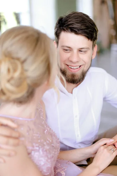 Jovem noiva loira sentada perto do noivo feliz e de mãos dadas . — Fotografia de Stock