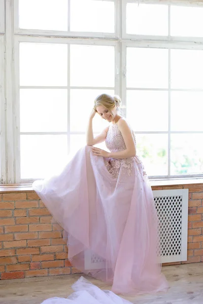 Blonde nevěsta stojí u okna a snění. — Stock fotografie