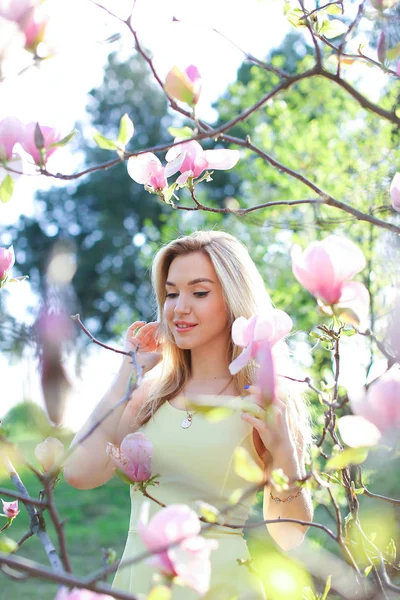 Ung trevlig kvinna stående nära magnolia i park. — Stockfoto