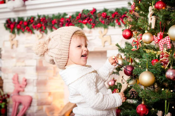 Kleines Mädchen schmückt Weihnachtsbaum am Kamin. — Stockfoto