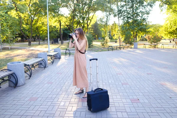 Jovem repórter vestindo vestido de pé fora com câmera e valise . — Fotografia de Stock