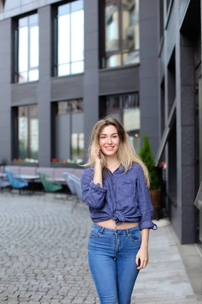 Menina sorridente falando por smartphone na cidade, vestindo jeans . — Fotografia de Stock