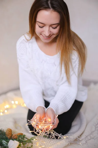 반짝 노란색 garlands 및 녹색 화 환으로 앉아 젊은 예쁜 여자. — 스톡 사진