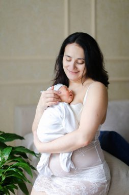 Yeni doğan bebek tutan giyen beyaz elbise genç mutlu anne.