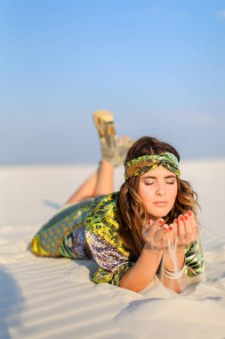 Genç kız beyaz kum üzerinde yalan yeşil beach bornoz giyiyor rahat. Sunbathe ve fotoğraf oturum kavramı çölde.