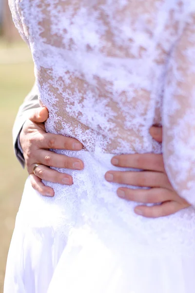 Male hands on bride back.