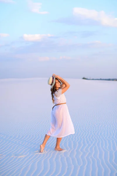 Молода жінка в білій сукні і капелюсі ходить на піску — стокове фото