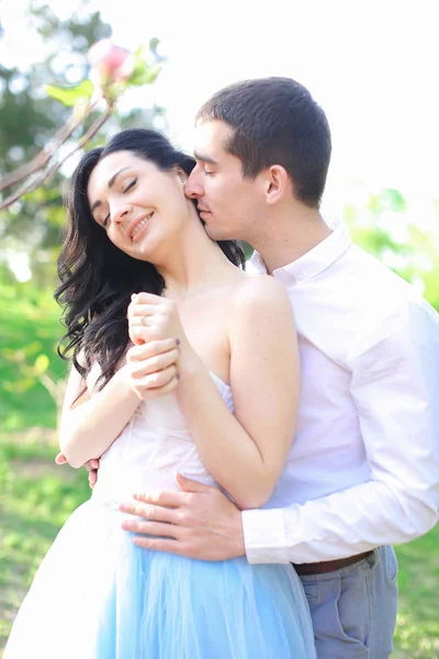 Brunette jonge man knuffelen en zoenen Kaukasische meisje in park. — Stockfoto