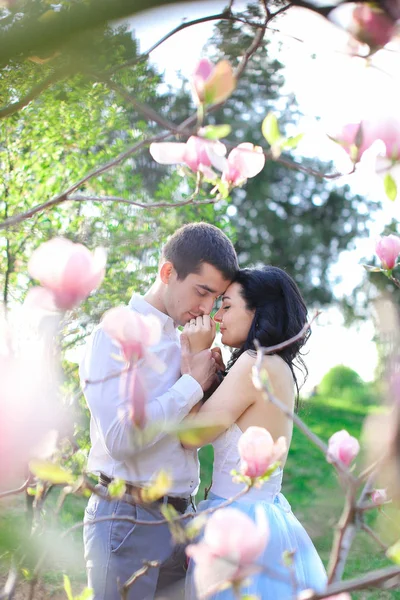Brunetka chłopiec amerykański, przytulanie i Całowanie dziewczynka kaukaski w pobliżu magnolia. — Zdjęcie stockowe
