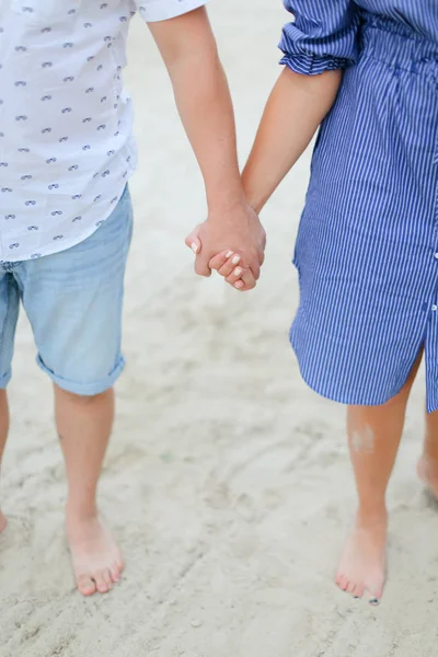 砂で裸足で歩く幸せなカップルの手を繋いでいるクローズ アップ. — ストック写真