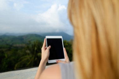 Tablet ve çekici fotoğraf Dağları arka planda kullanan genç sarışın kız.