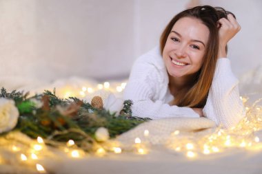 Genç Sevimli kadın yatakta yeşil çelenk ve sarı çelenk yakın yalan.