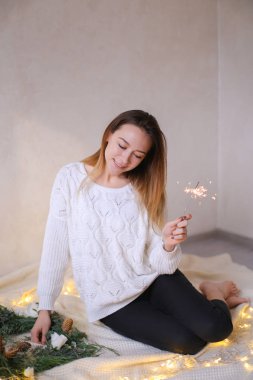 Bengal ışık parlayan sarı çelenk ve yeşil çelenk yakınında oturan genç Avrupa kadın.