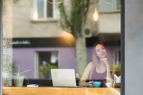 Молодая деловая женщина работает с ноутбуком в кафе и пьет кофе . — стоковое фото